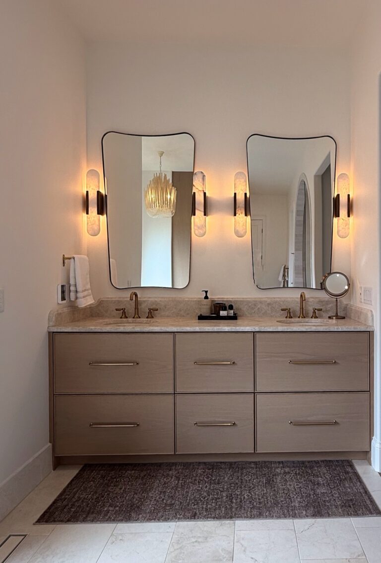 Floating double vanity with light oak drawers, brass pulls, stone top, two arched mirrors and alabaster sconces