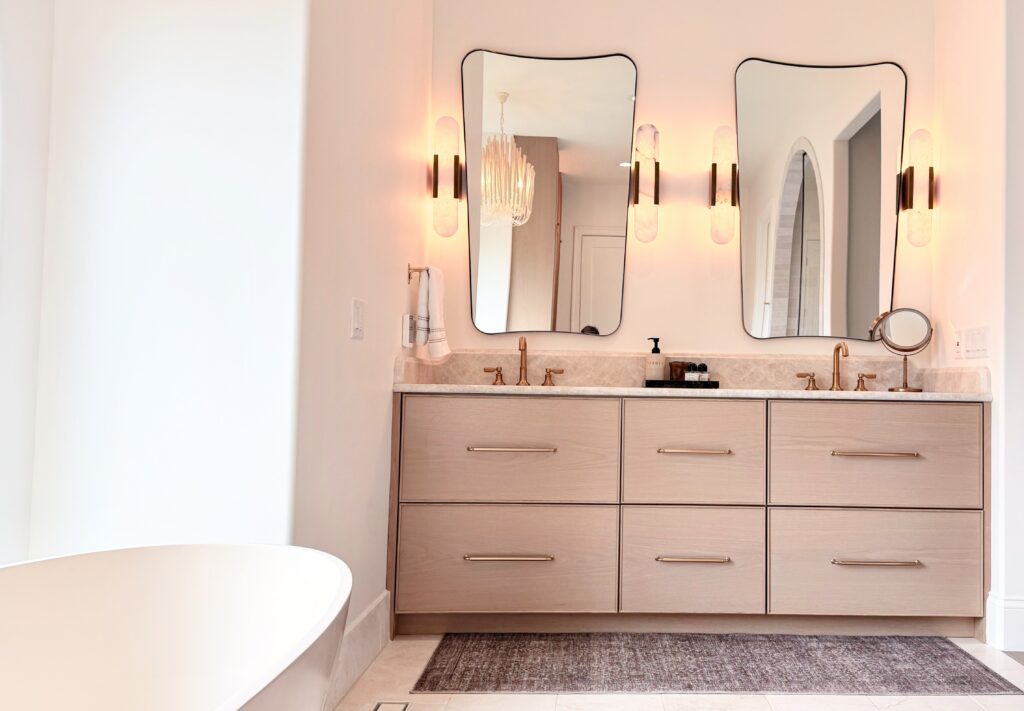 Floating white oak six-drawer double vanity with stone top, brass faucets, two shaped mirrors and sconces