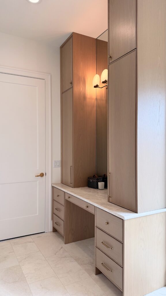 Light white oak bathroom vanity with makeup station, tall linen towers, marble top and brass pulls