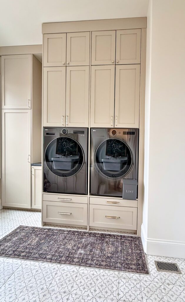 Greige shaker laundry cabinets around a raised washer and dryer