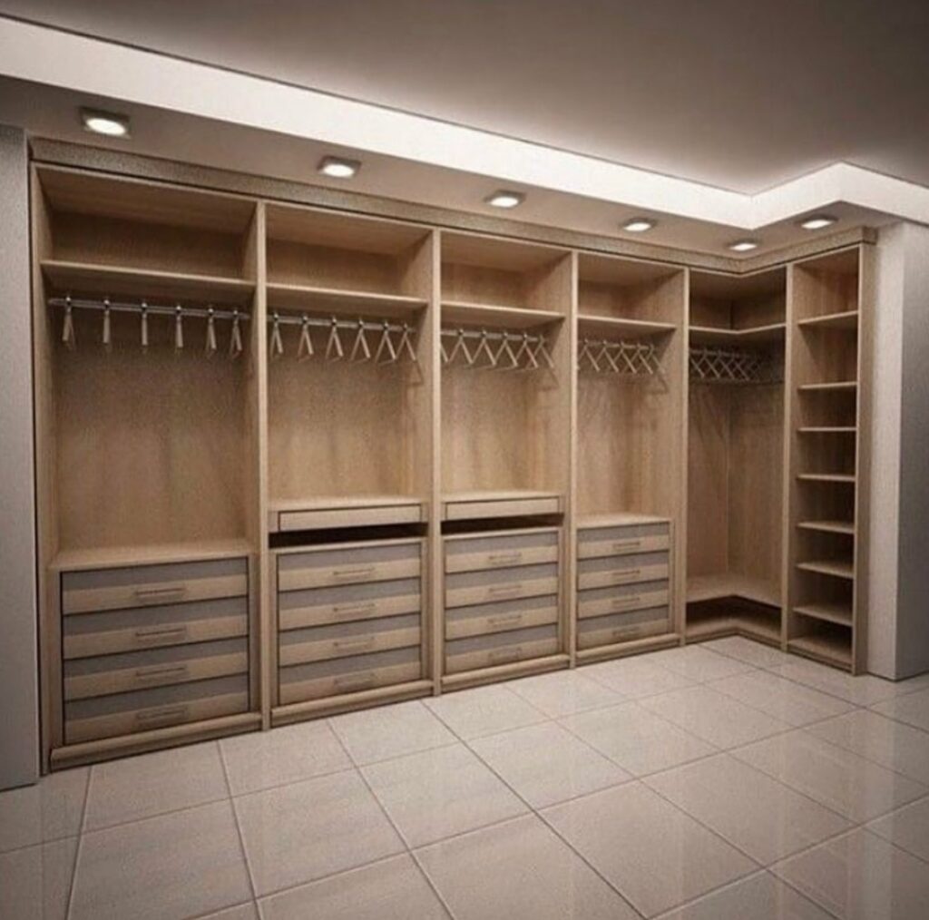 Open light oak walk-in closet with hanging rails and frosted drawer banks