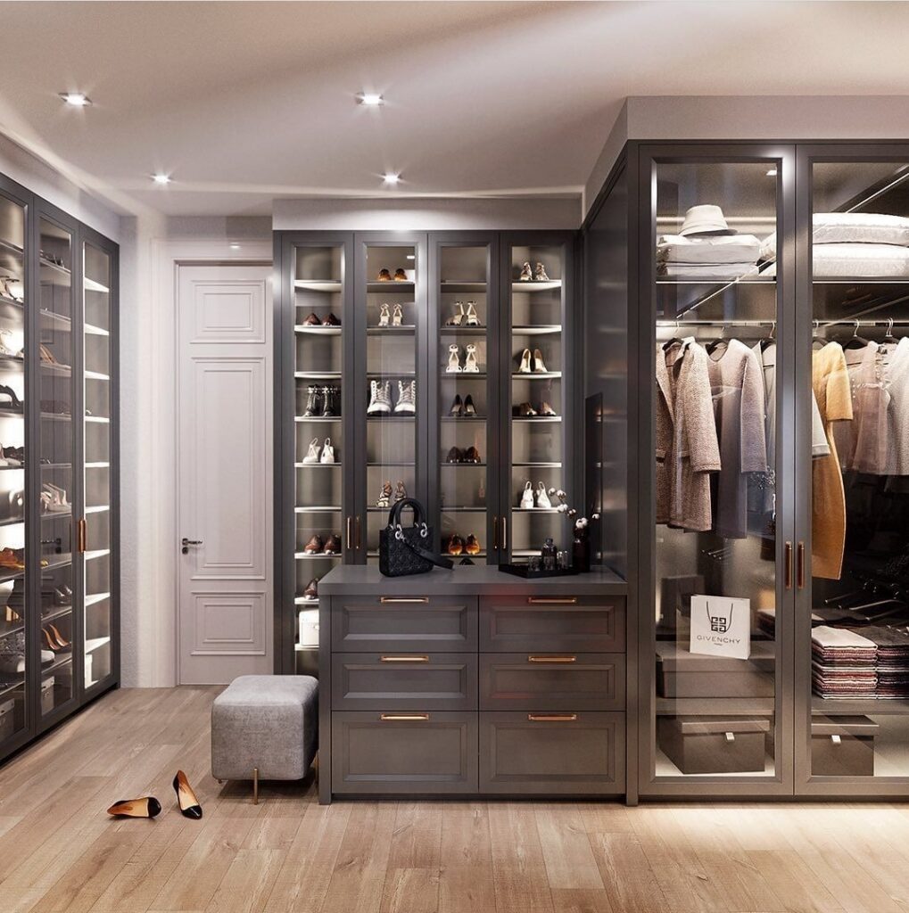 Walk-in closet with charcoal grey glass-front cabinets, lit shoe shelves, hanging rails and a drawer island