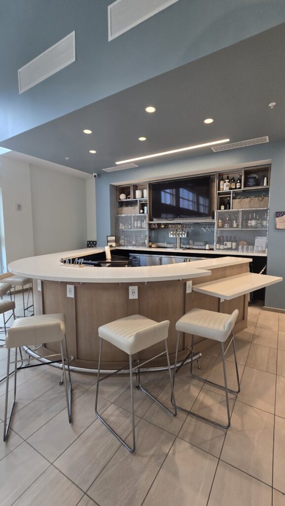 Curved hotel lobby bar in light wood veneer with a white quartz counter