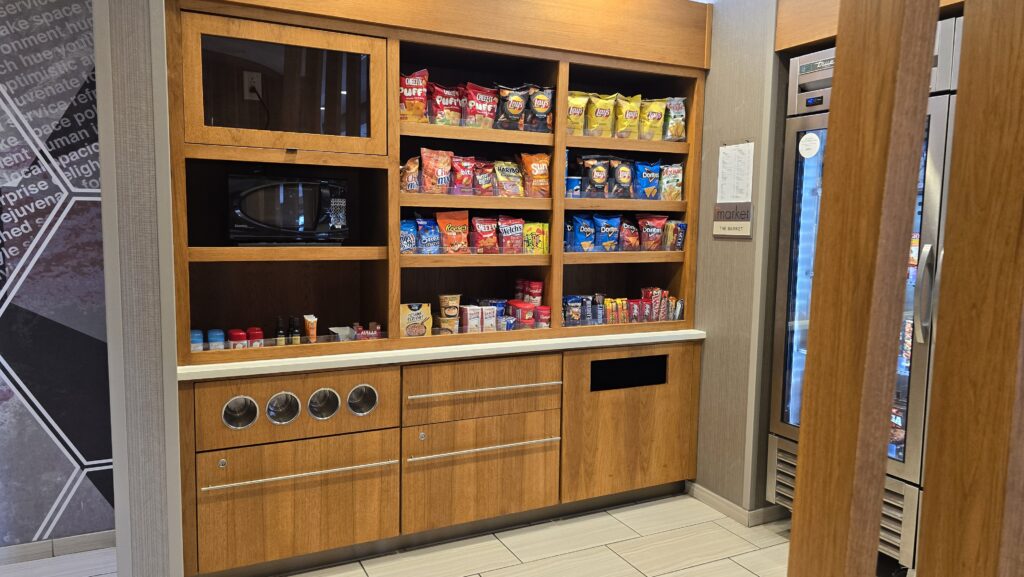 Built-in wood hotel pantry unit with snack shelves, microwave niche, cup dispensers and drawer base cabinets