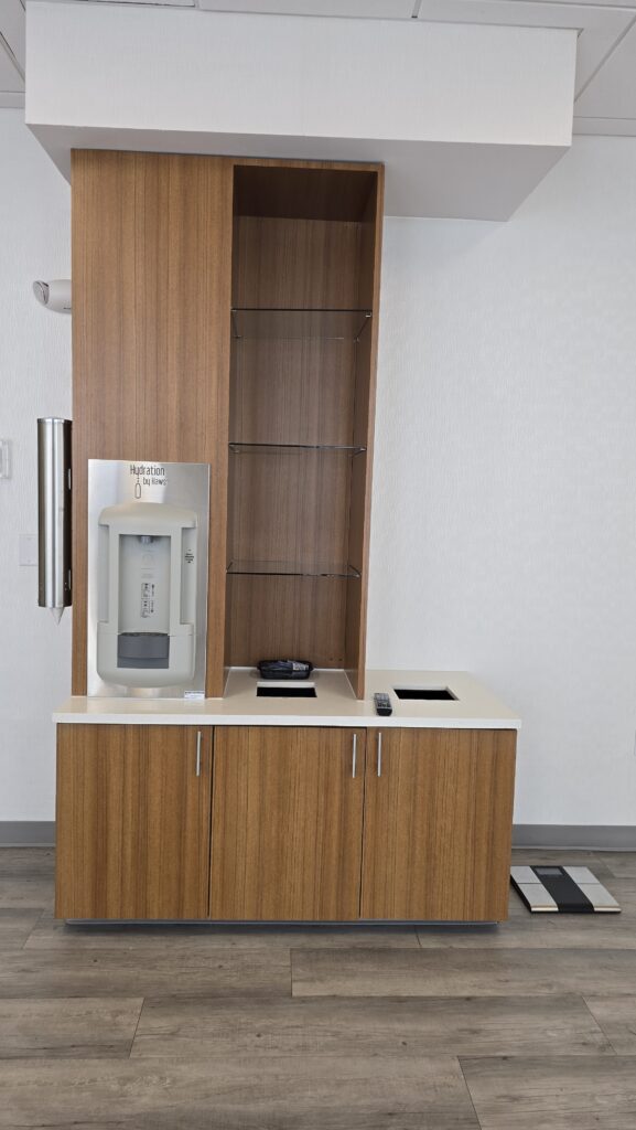 Wood-grain hydration station cabinet with open shelving tower, white quartz counter and water dispenser
