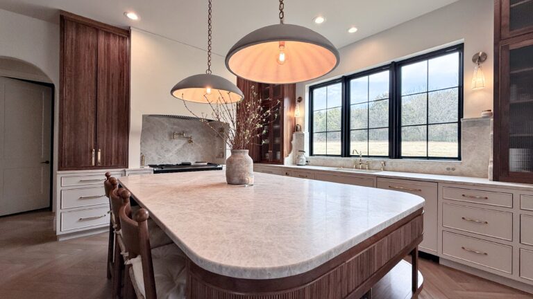 Kitchen with fluted walnut island, quartzite waterfall counter, cream perimeter cabinets and black steel windows