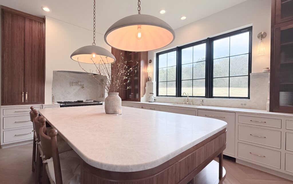 Kitchen with fluted walnut island, white marble waterfall top, cream perimeter cabinets and black grid windows