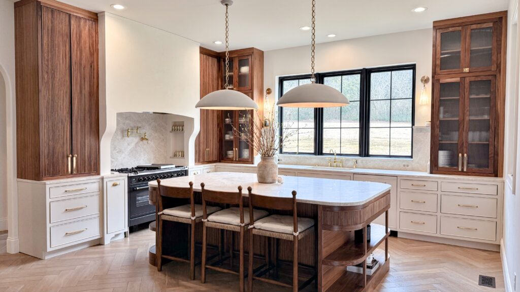 Two-tone kitchen with walnut cabinets, cream drawer bases, and a fluted walnut island